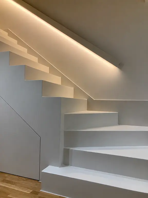Escalera interior revestida con acabado continuo MicroQuarz® e iluminación LED integrada.